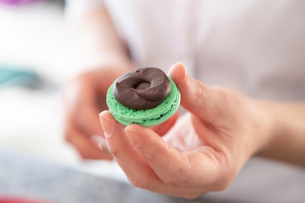 Menina preparando macarons com as mãos. Feche a foto.