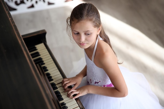 Menina princesa bonitinha toca piano no estúdio