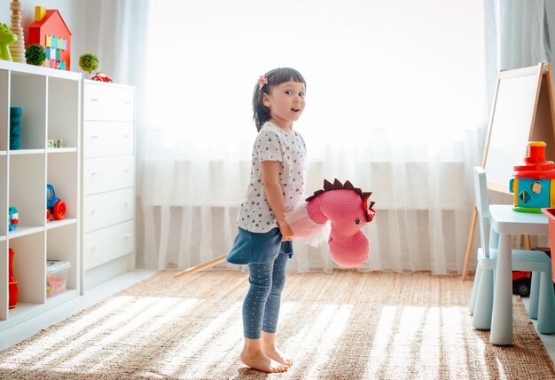 Menina pula e corre na vara de cavalo no berçário.