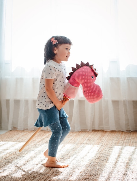 Menina pula e corre na vara de cavalo no berçário.