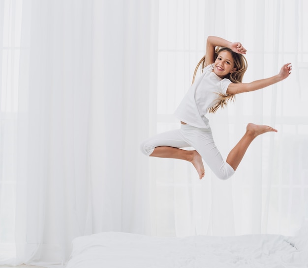 Foto menina pulando enquanto olha para a câmera