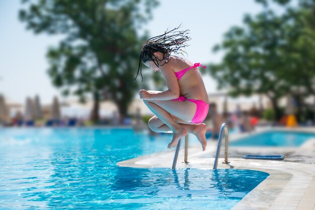 Menina pulando na piscina