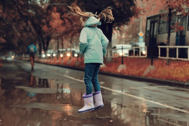 menina pulando nas poças na chuva de outono