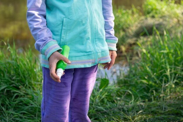 Menina pulveriza spray de mosquito na pele na natureza que morde suas mãos e pés Proteção contra picadas de insetos repelente seguro para crianças Recreação ao ar livre contra alergias Horário de verão