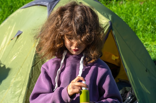 Menina pulveriza spray de mosquito na pele na natureza que morde suas mãos e pés Proteção contra picadas de insetos repelente seguro para crianças Recreação ao ar livre contra alergias Horário de verão