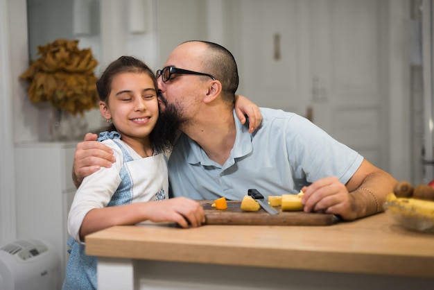 Menina que cozinha com um pai carinhoso e amoroso em uma cozinha moderna. Pai jovem feliz com filha bonita na cozinha.