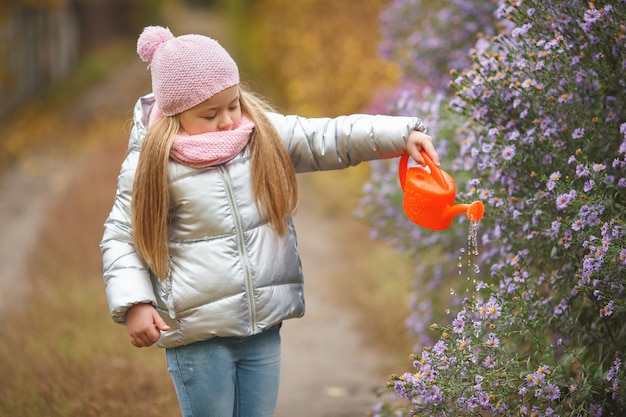 Menina regando as flores no jardim no outono