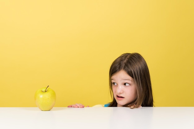 Menina rejeitando frutas isoladas em fundo amarelo