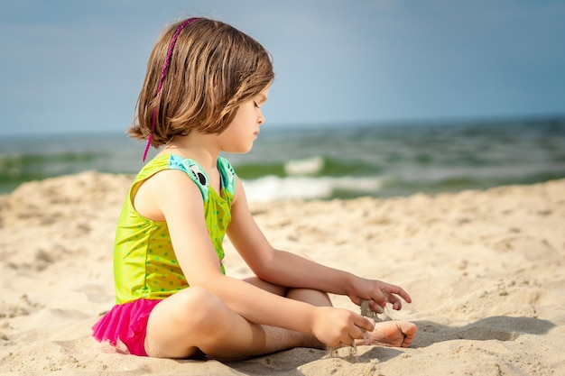 Menina relaxando na areia na praia contra o céu