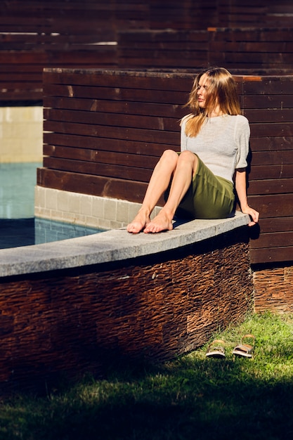 Menina relaxante sob o sol perto da água no dia quente sensual