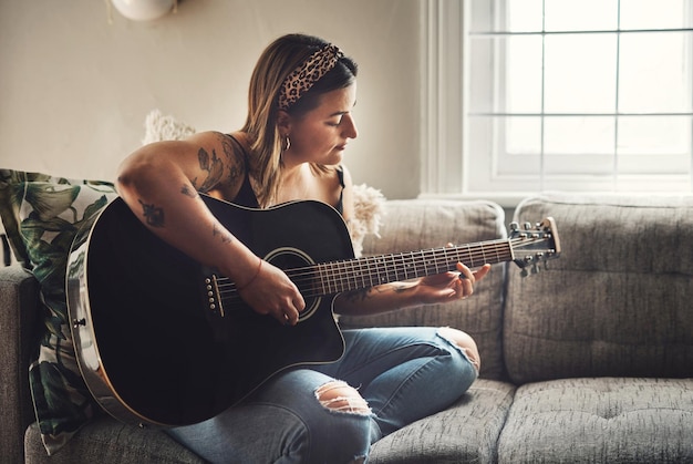 Menina relaxar e guitarra em casa para prática de música ou aprender acordes no sofá Instrumento de cordas musical mulher ou rastejando na sala de estar com desenvolvimento de tom de talento ou ensaio para desempenho