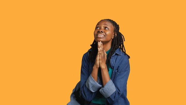Menina religiosa fazendo adoração fazendo gestos esperando por um milagre fundo de estúdio