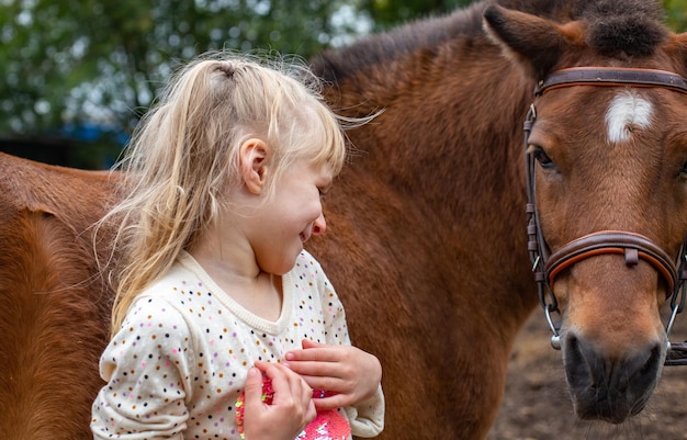 Foto menina rindo com cavalo de pônei no clube equestre