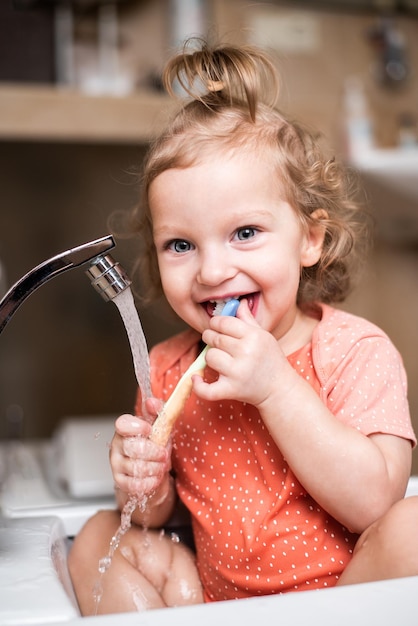 Menina rindo feliz escovando os dentes no banho