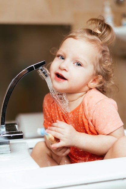 Menina rindo feliz escovando os dentes no banho