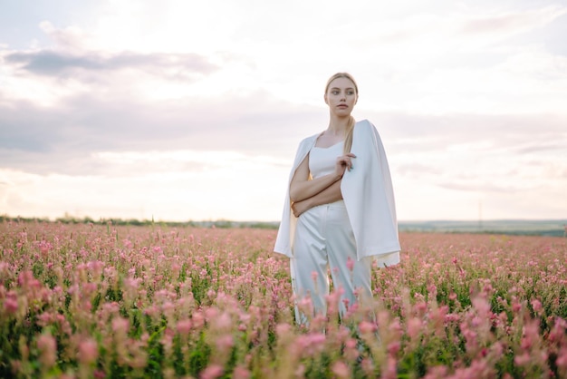 Menina romântica de beleza Ao ar livre ao pôr do sol Jovem mulher com roupas elegantes posando no campo florescente