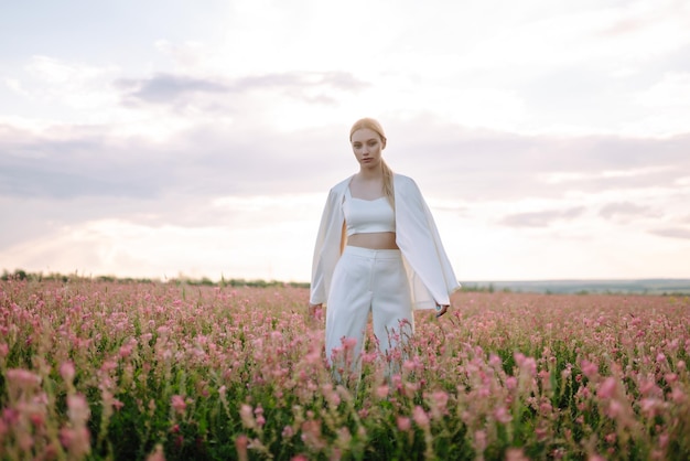Menina romântica de beleza Ao ar livre ao pôr do sol Jovem mulher com roupas elegantes posando no campo florescente