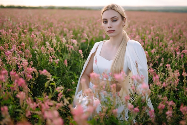 Menina romântica de beleza Ao ar livre ao pôr do sol Jovem mulher com roupas elegantes posando no campo florescente