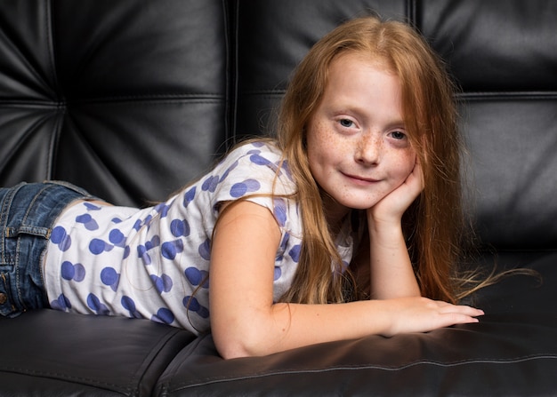 Menina ruiva com sardas descansando no sofá preto