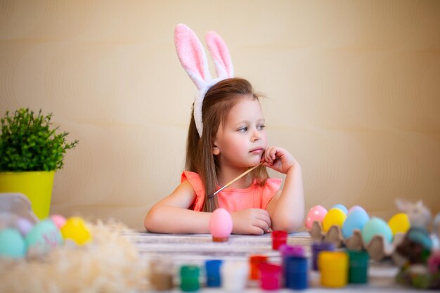 Menina ruiva em orelhas de coelho se prepara para a páscoa pintada ovos de páscoa feliz conceito de páscoa
