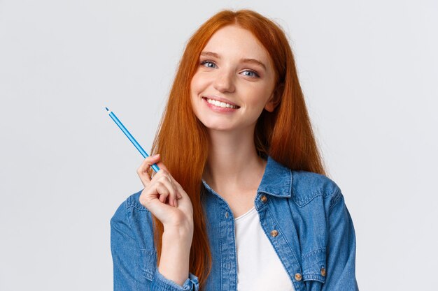 Menina ruiva segurando lápis colorido