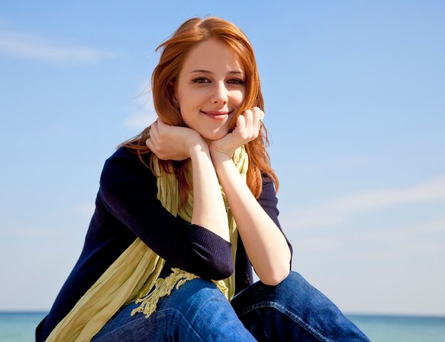 Menina ruivo bonita nova na praia no tempo de mola.