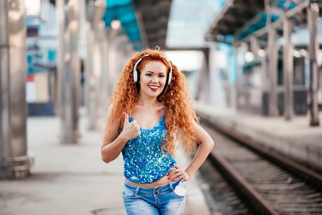 Menina ruivo que escuta a música em fones de ouvido.