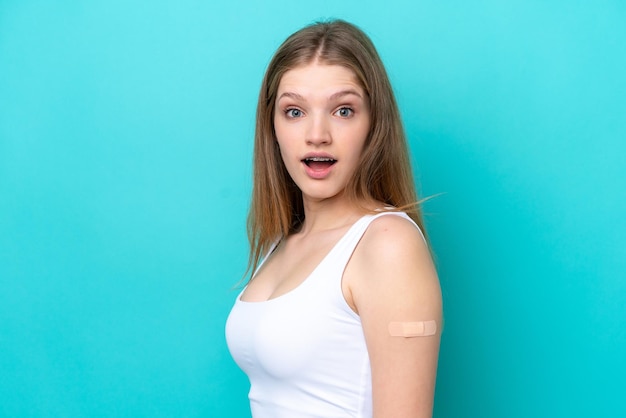 Menina russa adolescente usando um band-aids isolado em fundo azul com surpresa e expressão facial chocada