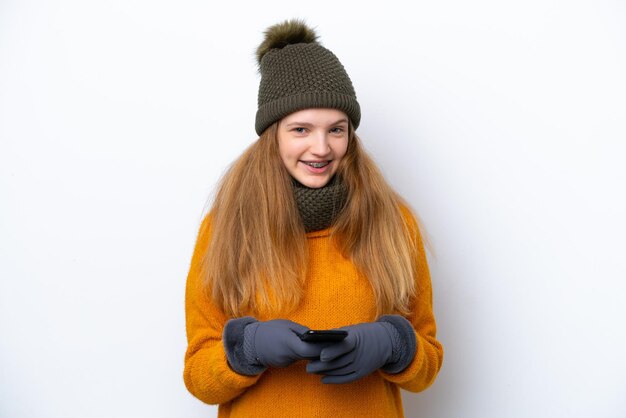 Menina russa adolescente vestindo jaqueta de inverno isolada em fundo branco enviando uma mensagem com o celular