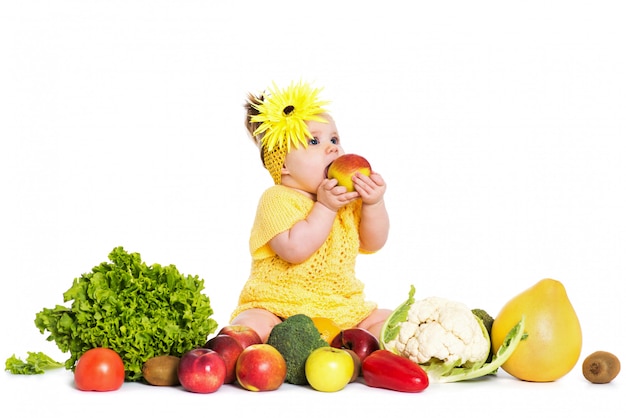 Foto menina são cercam de legumes e frutas, isoladas sobre o branco