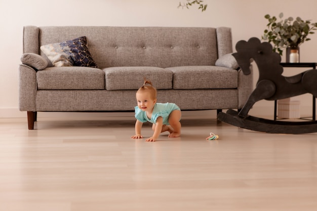 Menina saudável em uma sala ao lado de um sofá cinza está aprendendo a andar