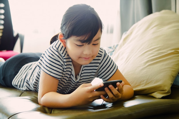 Menina se divertindo usando o smartphone em casa