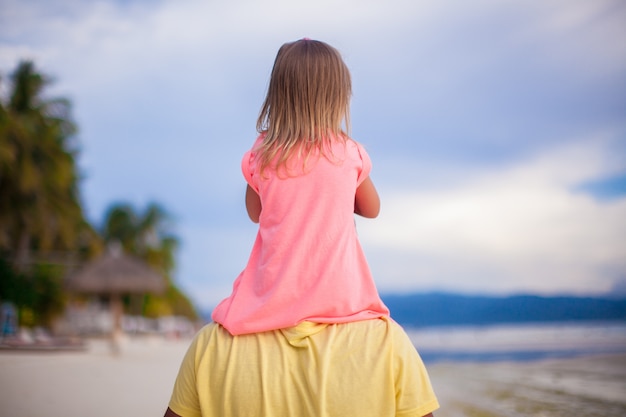 Menina se divertir com o pai na praia tropical