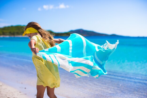 Menina se divertir com toalha de praia durante férias tropicais