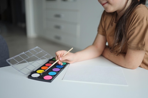 Menina se prepara para pintar em uma folha de papel em branco Desenho infantil Vista de cima