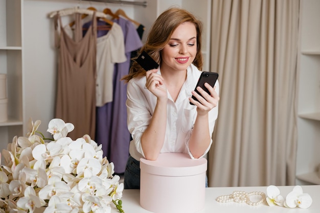 Foto menina segura um smartphone e um cartão bancário contra o fundo do guarda-roupa