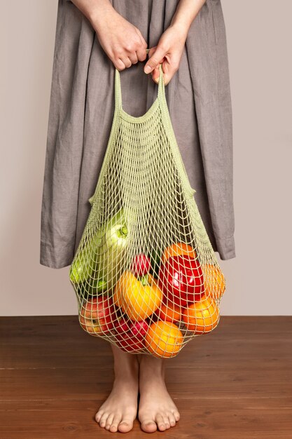 Menina segura uma sacola com frutas e legumes. o conceito de compras verdes e boa nutrição. entrega de produtos. proteção ambiental.