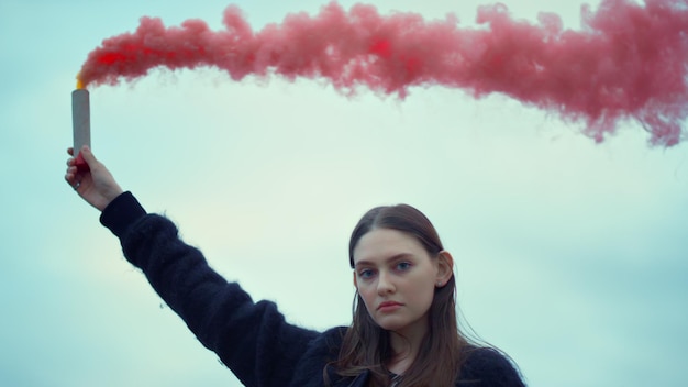 Menina segurando a bomba de fumaça na mão no protesto de rua Mulher usando granada de fumaça