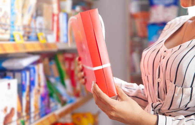 Menina segurando a caixa de doces no supermercado