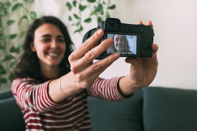 Foto menina segurando a câmera para gravar a si mesma em casa. foco seletivo na câmera