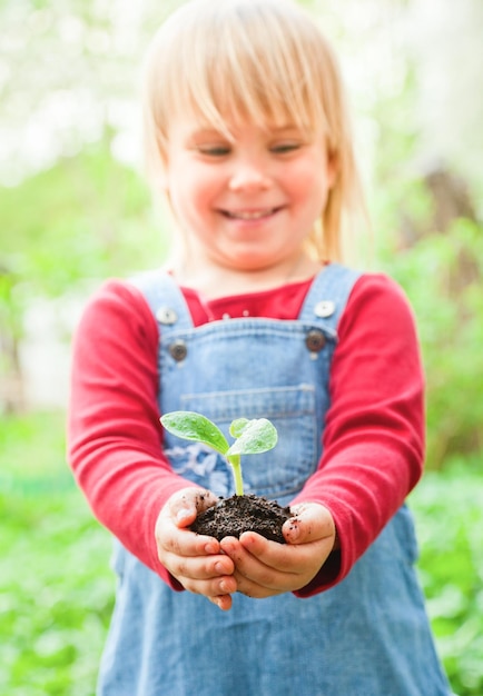 Menina segurando a semeadura com terra