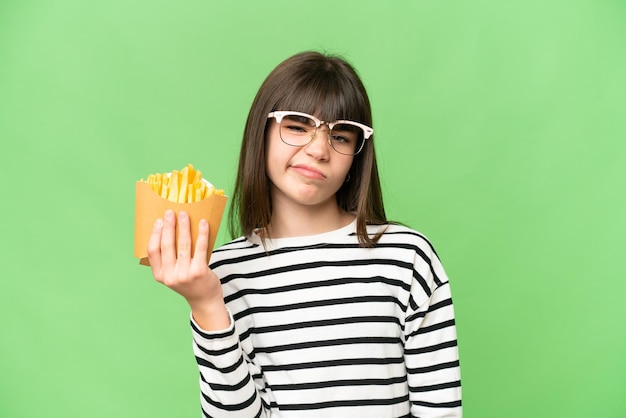 Menina segurando batatas fritas sobre fundo croma chave isolado com expressão triste