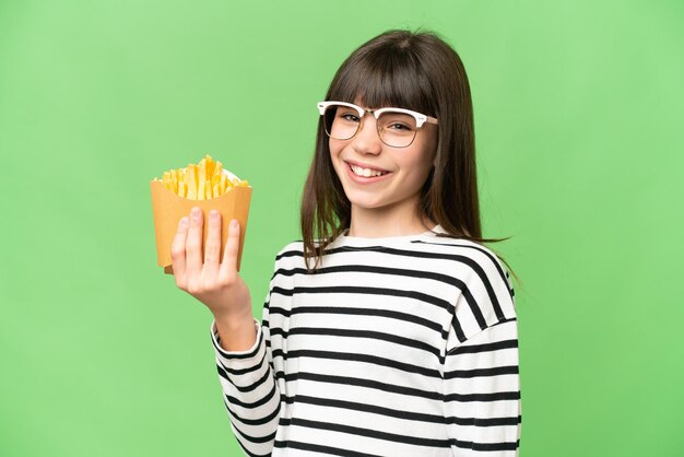 Menina segurando batatas fritas sobre fundo croma chave isolado sorrindo muito