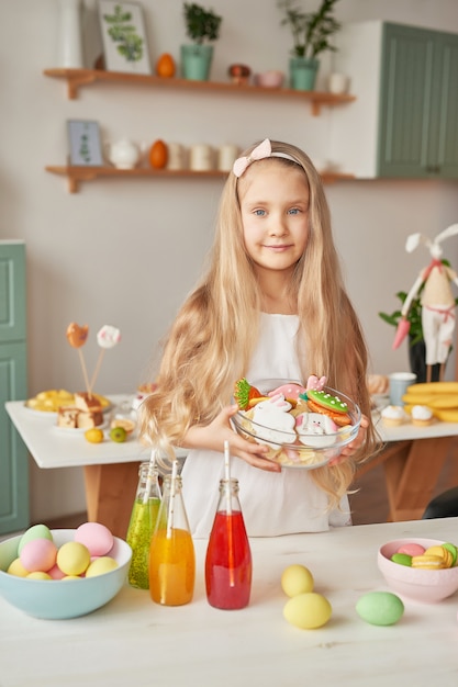 Menina segurando biscoitos de Páscoa na cozinha