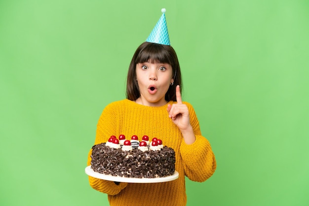 Menina segurando bolo de aniversário sobre fundo croma chave isolado com a intenção de perceber a solução enquanto levanta um dedo