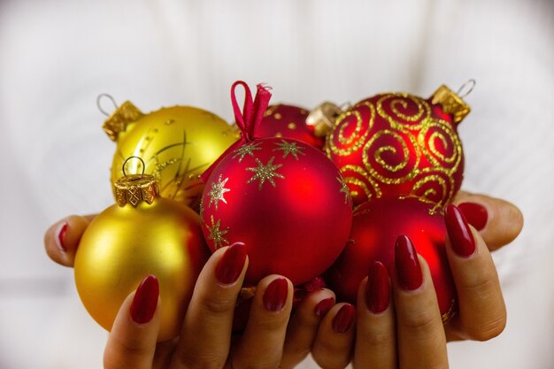 Foto menina segurando brinquedos, presentes e relógios de ano novo nas mãos dela. conceito de natal.