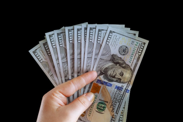 Menina segurando dólares na mão isolados no fundo preto. notas de cem dólares. moeda americana.