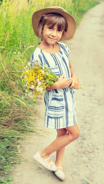 Menina segurando flores silvestres nas mãos de uma criança. Foco seletivo.