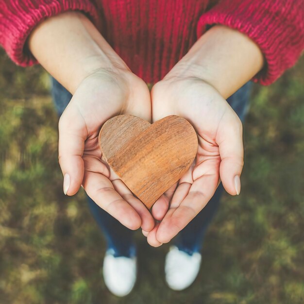 Foto menina segurando forma de madeira de coração conceito para dar amor