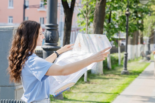 Menina segurando mapa turístico procurando caminho viajando em pé sobre fundo branco